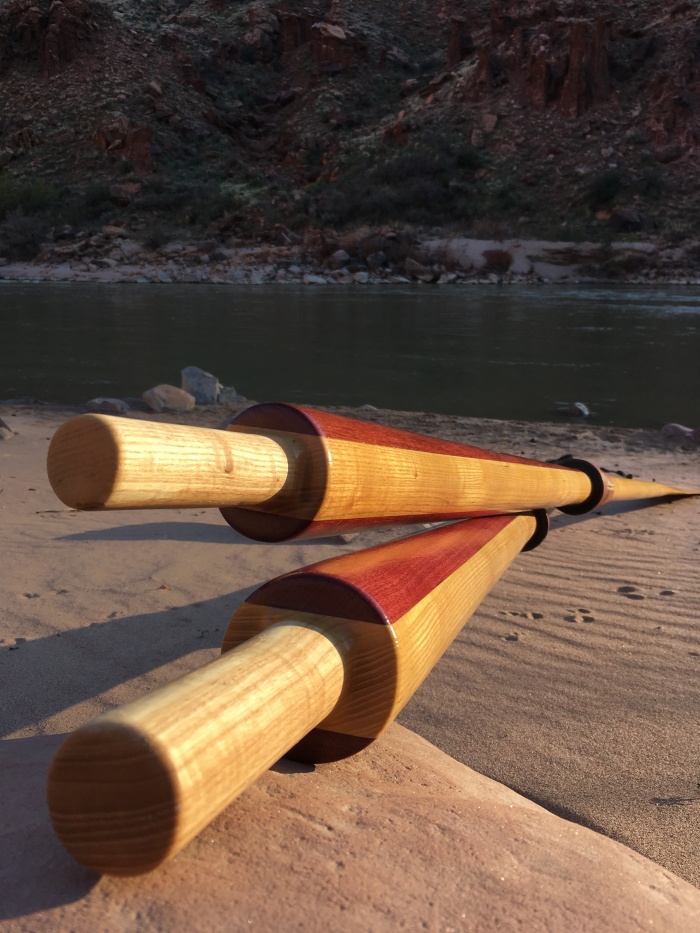 Two handmade wood oars lying by the Colorado River near Moab Utah. Oars are two-toned from the blonde ash and purpleheart wood used in the upper portions.